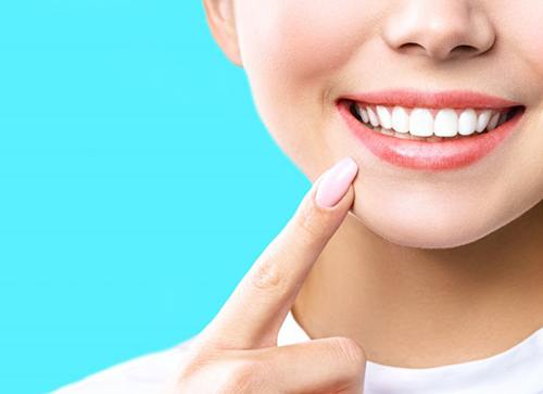 Close up of woman touching a finger to her smile