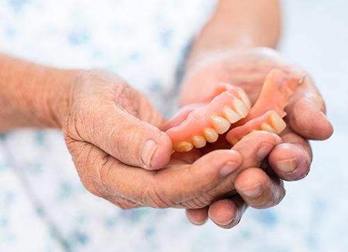 Someone holding a pair of dentures