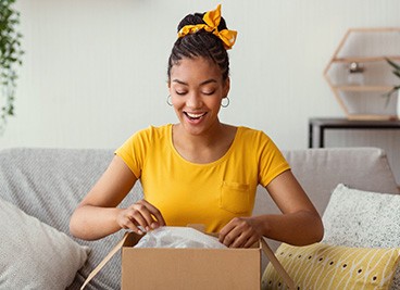 Woman smiling while opening package on couch
