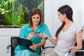 A woman paying the cost of Invisalign