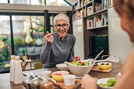 Smiling woman eating lunch at kitchen table with friend