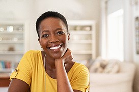 Woman in yellow shirt smiling at home